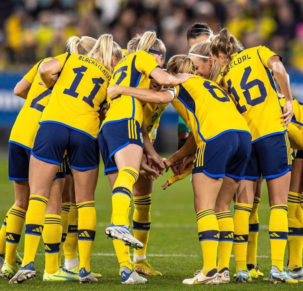 Jogadoras da seleção da Suécia de futebol feminino se juntam e dão as mãos antes de uma partida