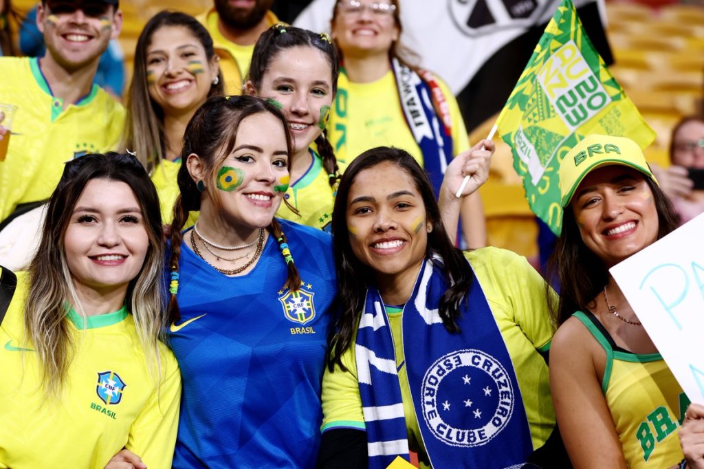 Foto de torcedoras da Seleção Brasileira durante partida da equipe na Copa do Mundo Feminina. Em primeiro plano, quatro delas aparecem vestindo a camisa do Brasil