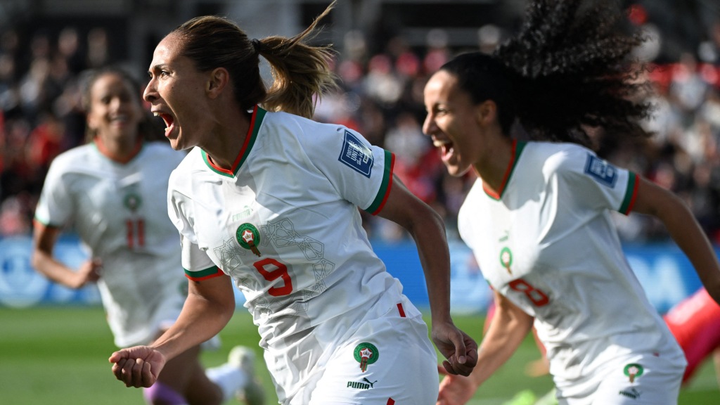 Ibtissam Jraïdi, camisa nove da seleção de Marrocos, corre e grita para comemorar o gol marcado contra a Coreia do Sul. Ao fundo, duas companheiras correm junto