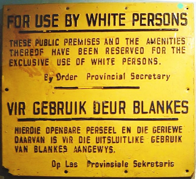 Placa amarela com letras pretas anuncia, em inglês e africâner, que o local era para uso exclusivo de pessoas brancas, na África do Sul